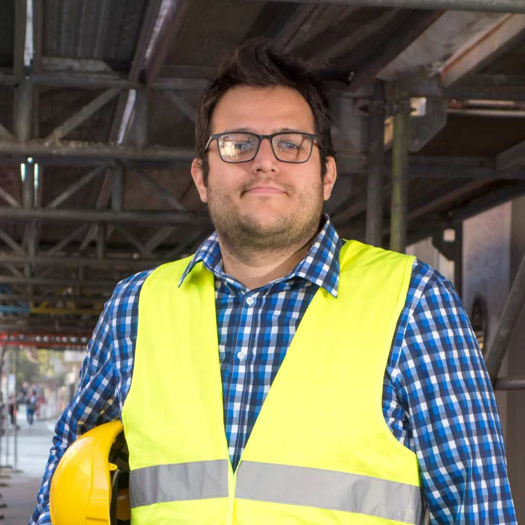 Contractor in a safety vest holding his hard hat at a job site